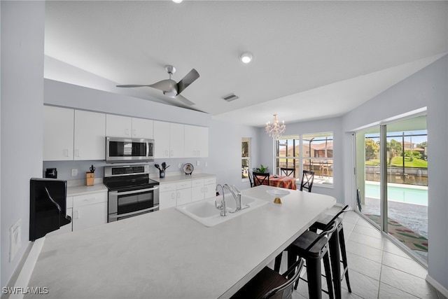 kitchen with a kitchen breakfast bar, a sink, visible vents, stainless steel appliances, and light countertops