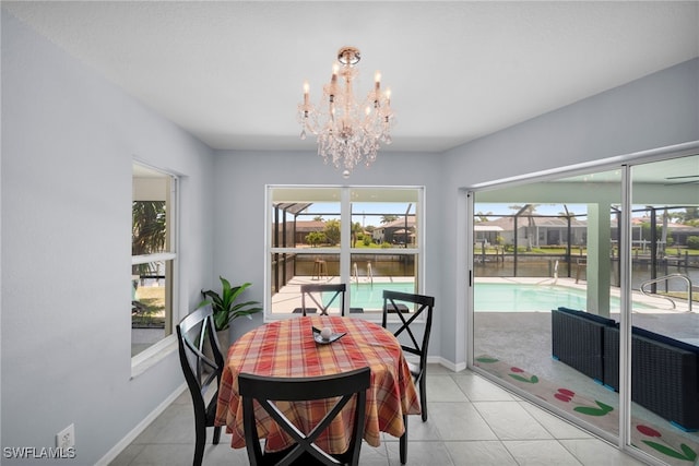 dining room featuring light tile patterned flooring, a notable chandelier, a water view, and baseboards