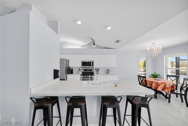 kitchen featuring a sink, stainless steel appliances, a kitchen breakfast bar, a peninsula, and light countertops