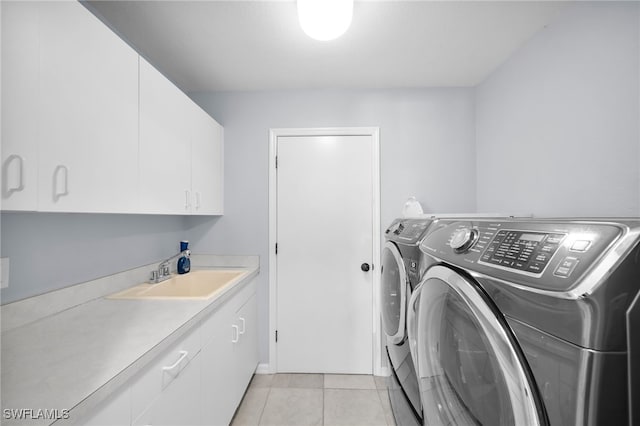 laundry area with light tile patterned floors, washing machine and dryer, a sink, and cabinet space