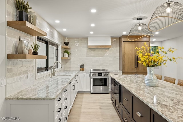 kitchen with pendant lighting, stainless steel electric range, sink, light stone countertops, and white cabinetry