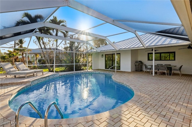 view of swimming pool featuring a patio, glass enclosure, and ceiling fan