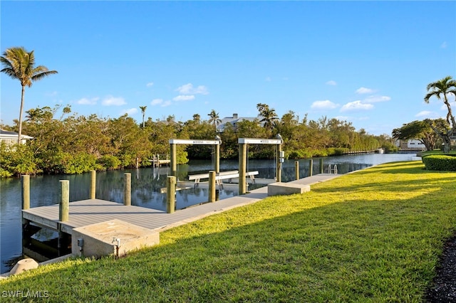 view of dock with a lawn and a water view