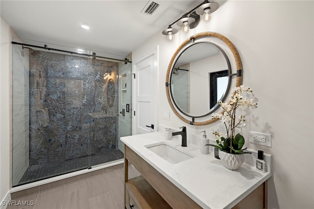 bathroom featuring a shower with door and vanity