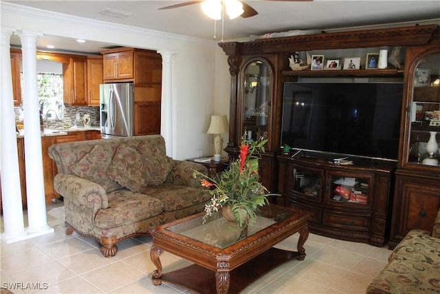 tiled living room with ornate columns, ceiling fan, crown molding, and sink