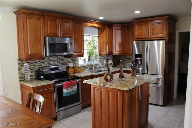 kitchen with sink, light stone countertops, light tile patterned floors, a kitchen island, and stainless steel appliances