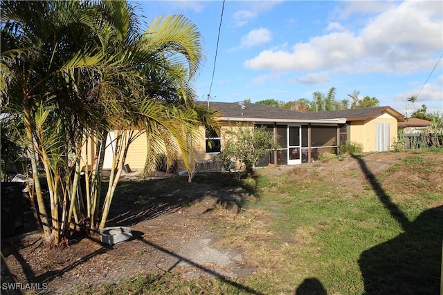 rear view of house featuring a yard and a sunroom