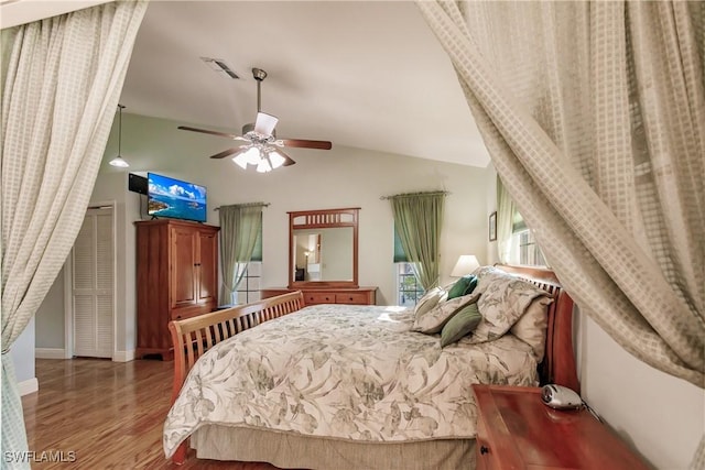 bedroom with baseboards, visible vents, a ceiling fan, wood finished floors, and vaulted ceiling