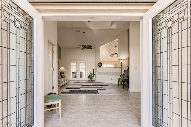 corridor with french doors, a towering ceiling, and light tile patterned flooring