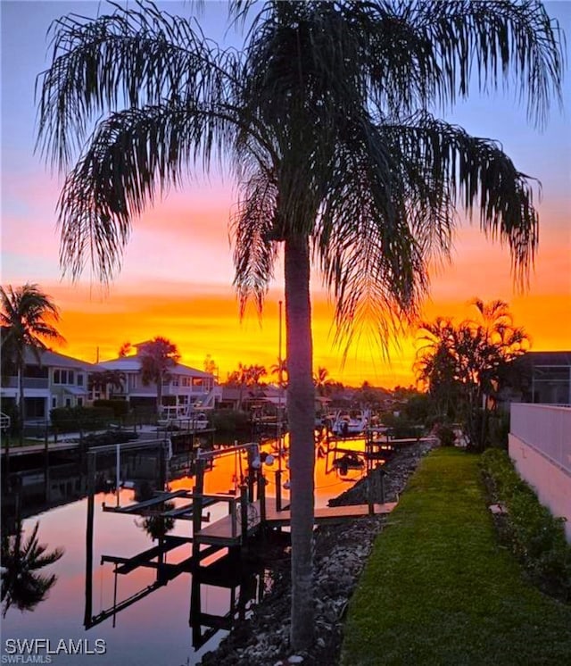 view of community with a boat dock, boat lift, and a lawn