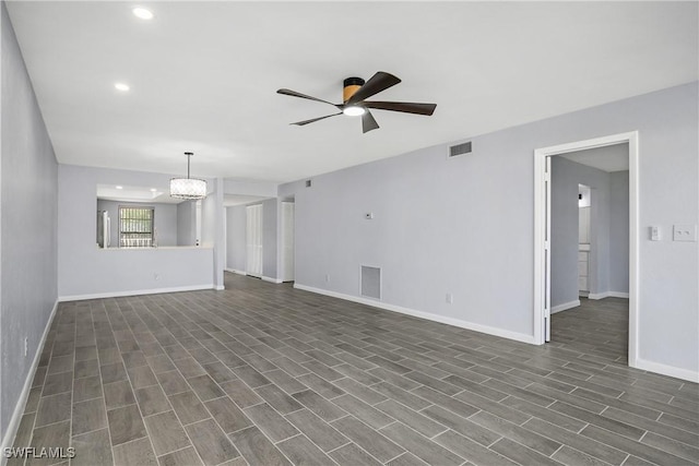 unfurnished living room featuring ceiling fan with notable chandelier and dark hardwood / wood-style flooring