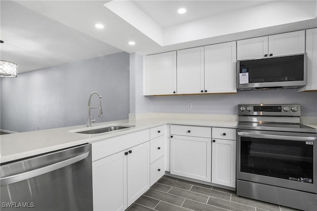 kitchen featuring appliances with stainless steel finishes, sink, pendant lighting, and white cabinets