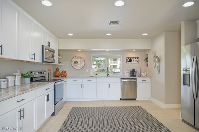 kitchen with light stone counters, stainless steel appliances, sink, white cabinets, and light tile patterned flooring