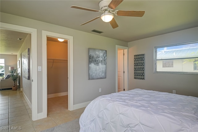 bedroom featuring a walk in closet, ceiling fan, a closet, and light tile patterned flooring