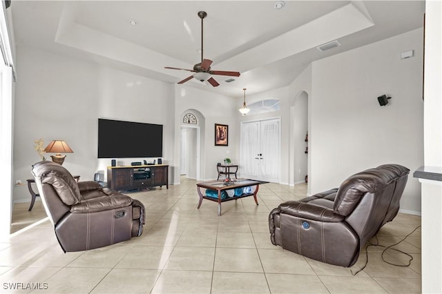 living room featuring ceiling fan, light tile patterned floors, and a tray ceiling