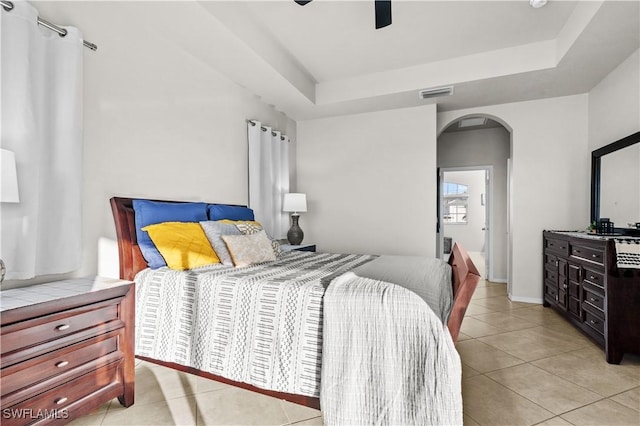 bedroom featuring ceiling fan, a raised ceiling, and light tile patterned floors