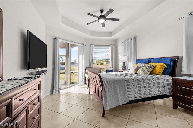 bedroom featuring a raised ceiling, ceiling fan, light tile patterned flooring, and access to exterior