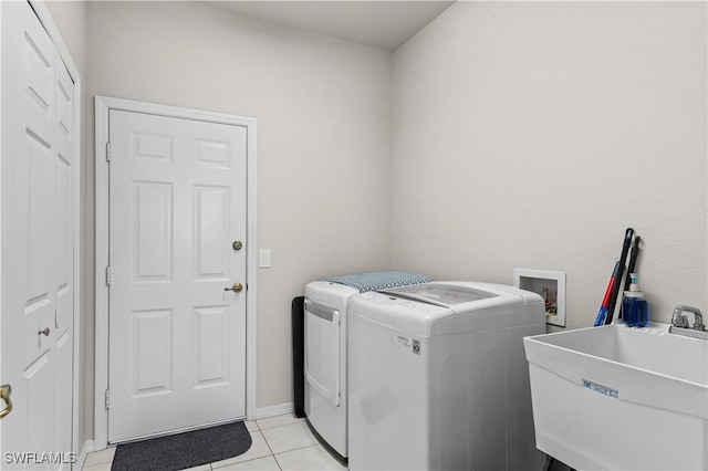 washroom featuring washing machine and clothes dryer, sink, and light tile patterned flooring