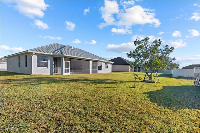 rear view of property featuring a sunroom and a lawn