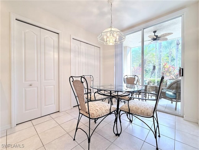 tiled dining room featuring a wealth of natural light and ceiling fan with notable chandelier