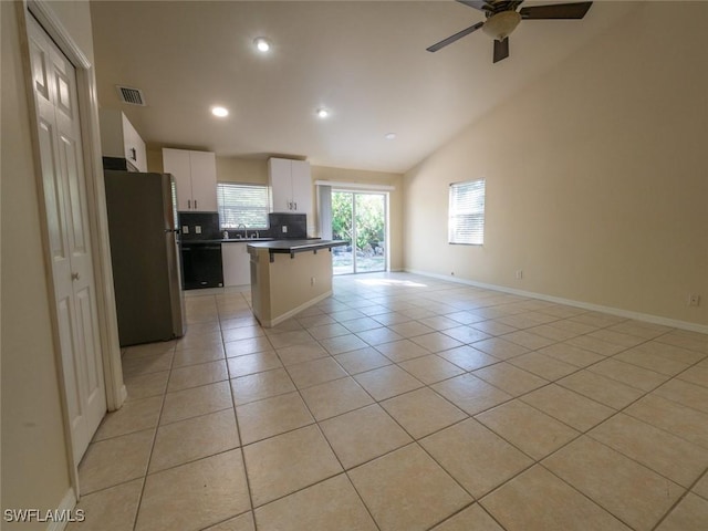 kitchen featuring a center island, white cabinets, stainless steel fridge, light tile patterned floors, and a kitchen bar