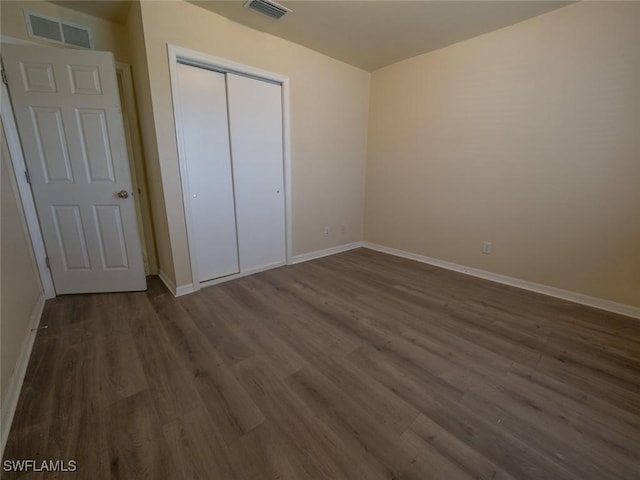 unfurnished bedroom with dark hardwood / wood-style flooring and a closet