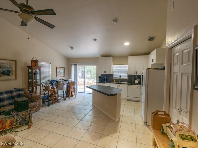 kitchen with white appliances, white cabinets, sink, vaulted ceiling, and light tile patterned floors