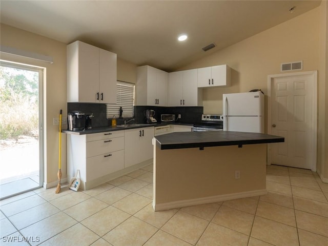 kitchen with white fridge, a kitchen island, white cabinetry, and vaulted ceiling