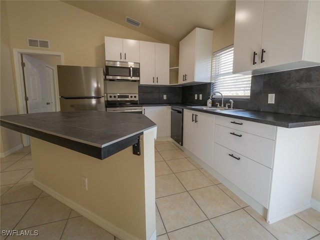 kitchen with white cabinetry, a center island, sink, stainless steel appliances, and vaulted ceiling