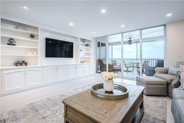 living room with built in shelves, floor to ceiling windows, and ceiling fan