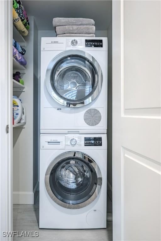 clothes washing area with stacked washer and dryer and light hardwood / wood-style floors