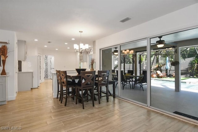 dining space with ceiling fan with notable chandelier