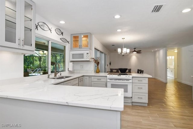 kitchen with white cabinetry, sink, kitchen peninsula, pendant lighting, and white appliances