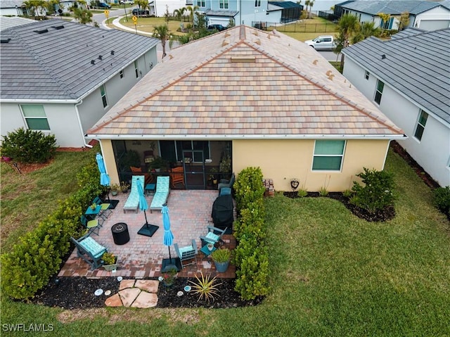 back of house with an outdoor living space with a fire pit, a yard, and a patio