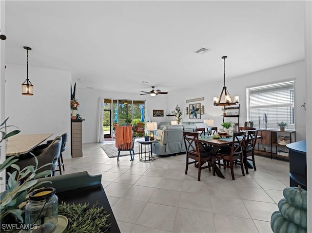 tiled dining room with ceiling fan with notable chandelier