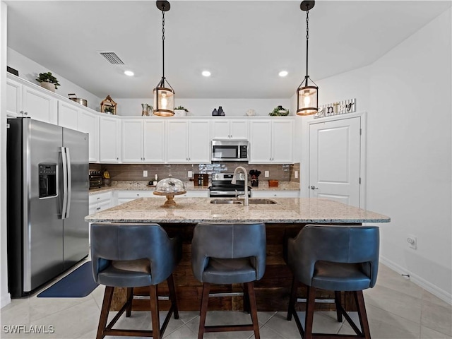 kitchen with sink, white cabinetry, stainless steel appliances, and an island with sink