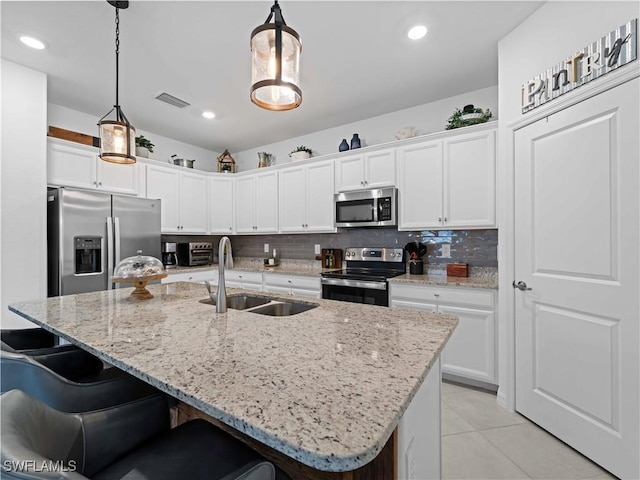 kitchen featuring appliances with stainless steel finishes, a kitchen island with sink, and pendant lighting