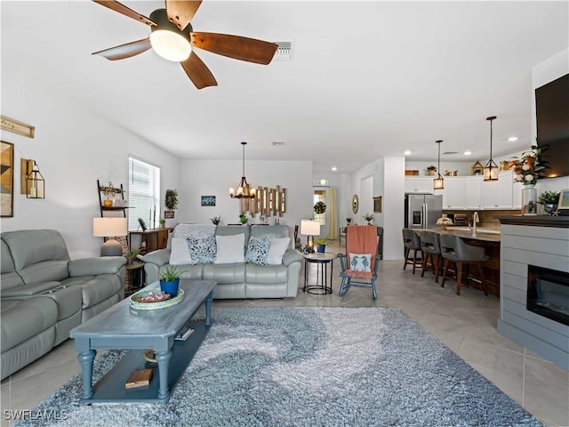 tiled living room featuring ceiling fan with notable chandelier