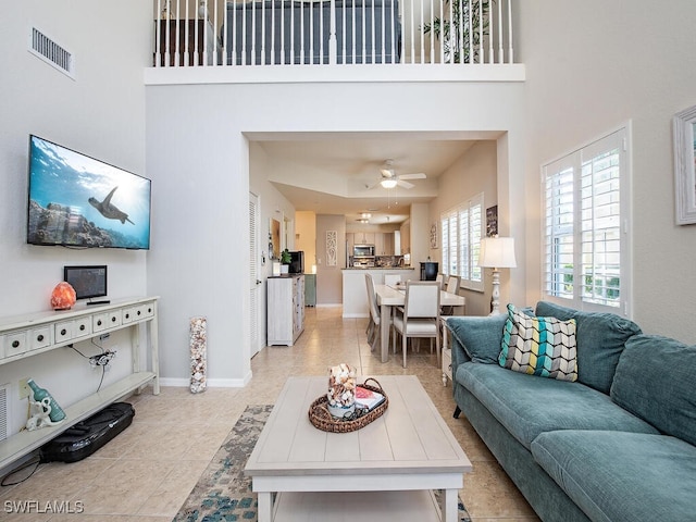 tiled living room featuring ceiling fan and a towering ceiling