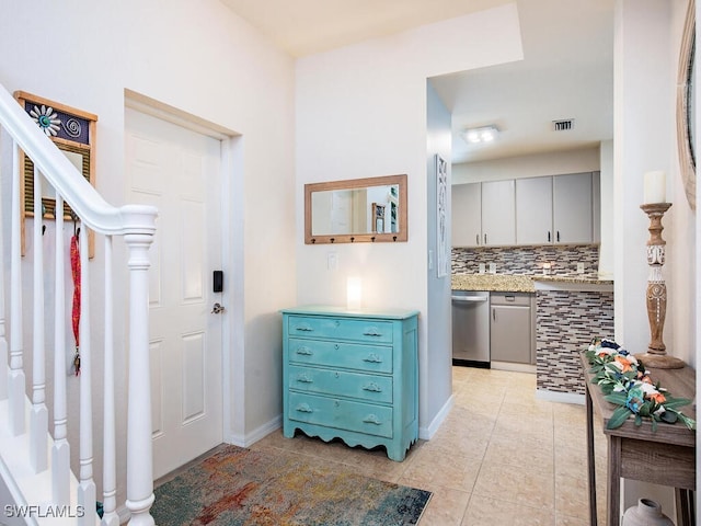 interior space featuring dishwasher, light tile patterned flooring, and decorative backsplash