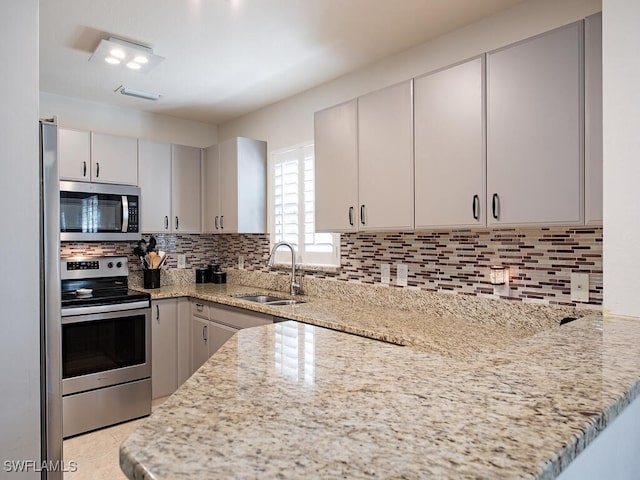 kitchen with tasteful backsplash, sink, light stone countertops, and appliances with stainless steel finishes