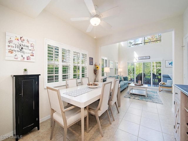 tiled dining space with a towering ceiling and ceiling fan