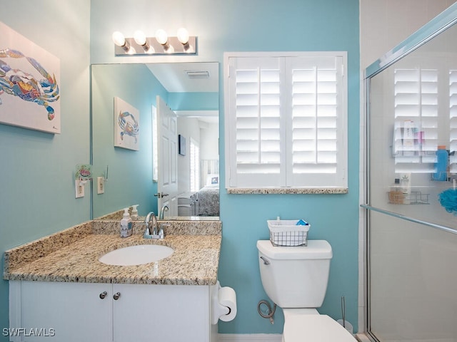 bathroom featuring vanity, a shower with shower door, and toilet