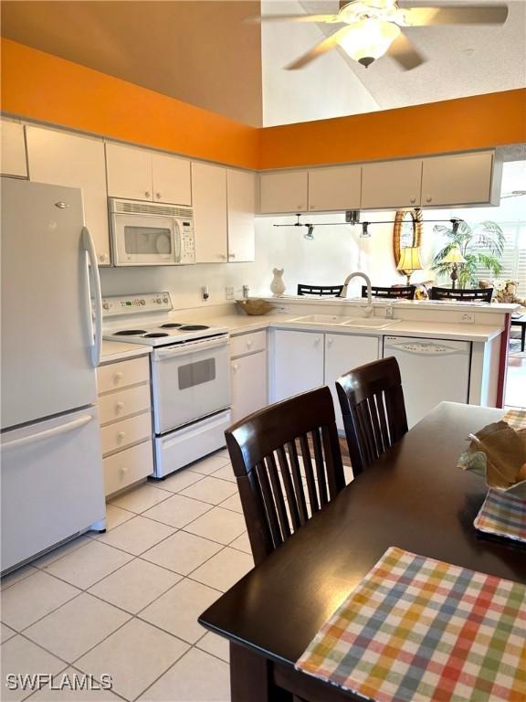 kitchen with light tile patterned flooring, sink, white cabinets, and white appliances