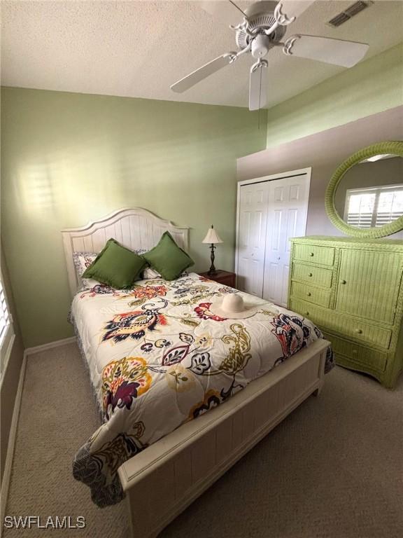 carpeted bedroom with ceiling fan, a closet, and a textured ceiling