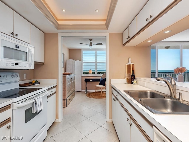 kitchen with a raised ceiling, white cabinets, and white appliances