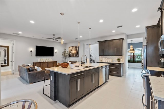 kitchen with ceiling fan, a kitchen island with sink, decorative light fixtures, and appliances with stainless steel finishes