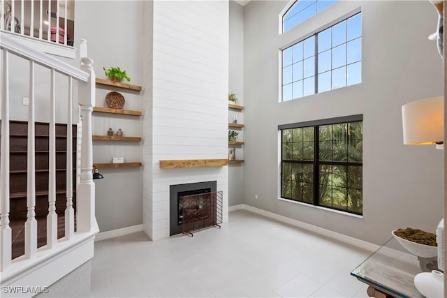 living room with a fireplace, a towering ceiling, and a wealth of natural light