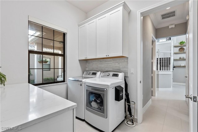 washroom featuring washer and clothes dryer, light tile patterned flooring, and cabinets