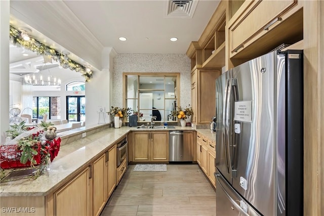 kitchen with kitchen peninsula, appliances with stainless steel finishes, french doors, sink, and a chandelier